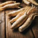 Korean white ginseng roots laid out on a rustic wooden table. The focus is on the roots' natural textures, shapes,